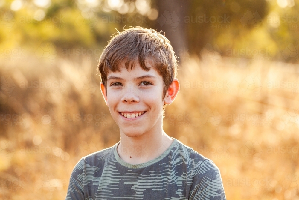 Portrait of a pre-teen boy in rural Australia outside in golden light with paddock backdrop - Australian Stock Image