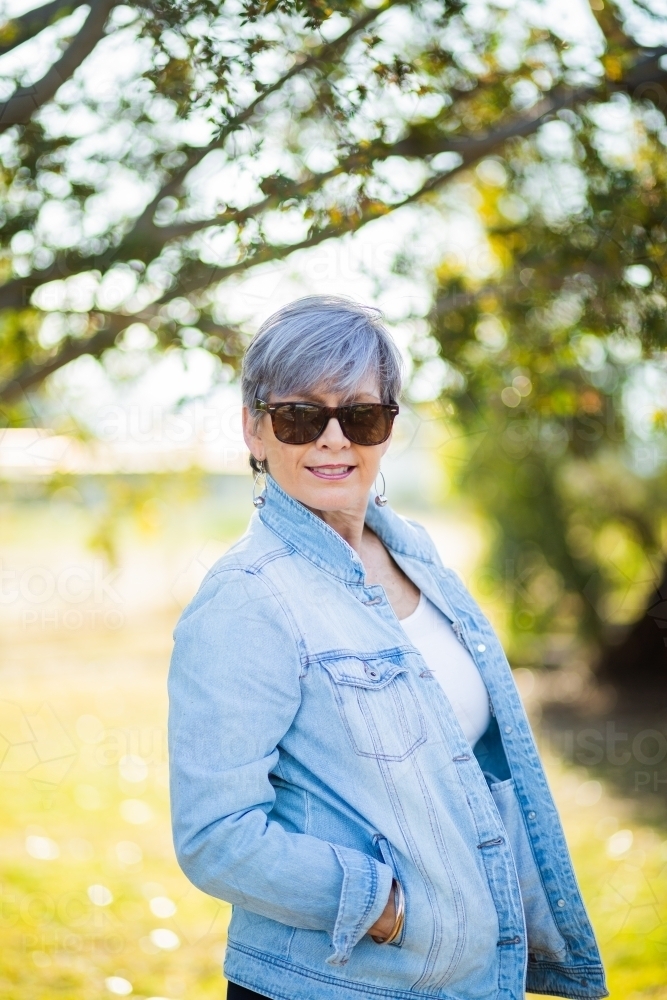 portrait of a senior woman in the garden wearing sunglasses - Australian Stock Image