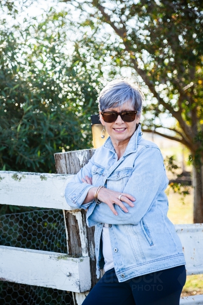 portrait of a senior woman in the garden wearing sunglasses - Australian Stock Image