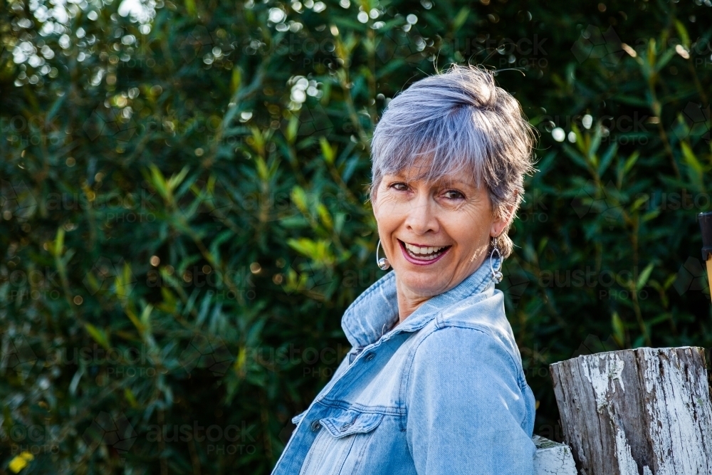 portrait of a senior woman smiling in the garden - Australian Stock Image