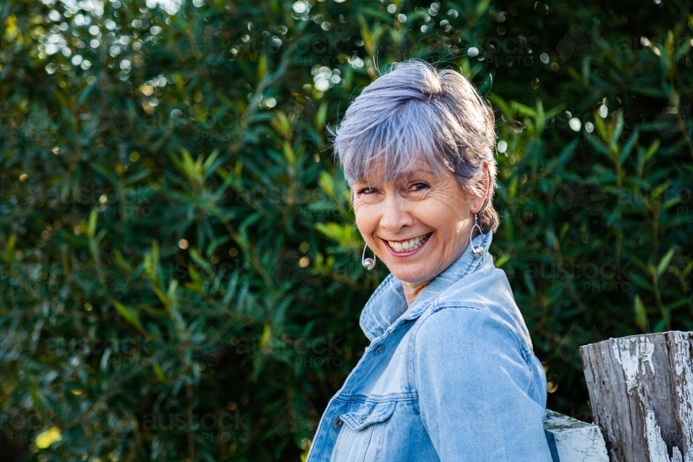 portrait of a senior woman smiling in the garden - Australian Stock Image