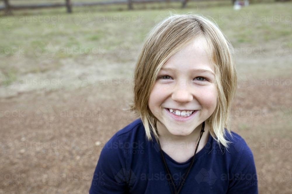 Portrait of a smiling blonde girl standing outside - Australian Stock Image