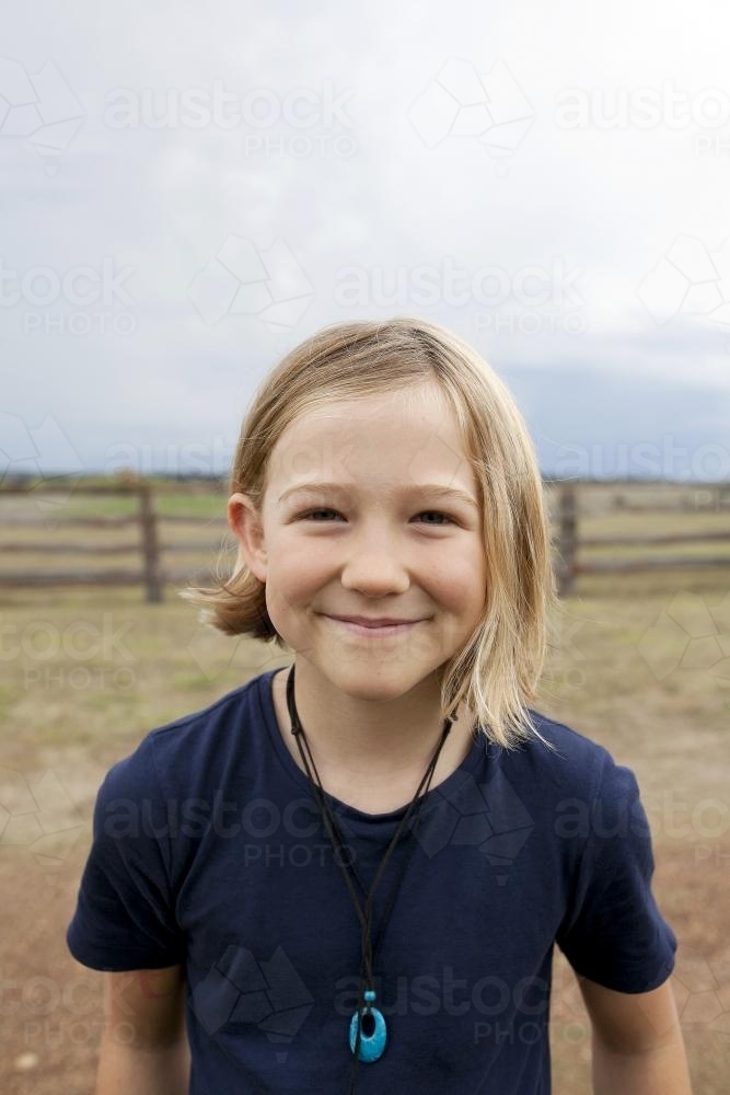 Portrait of a smiling blonde girl standing outside on farm - Australian Stock Image