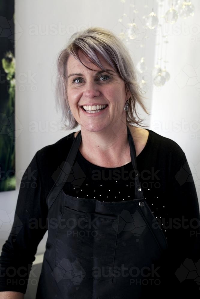 Portrait of a smiling hairdresser wearing an apron - Australian Stock Image