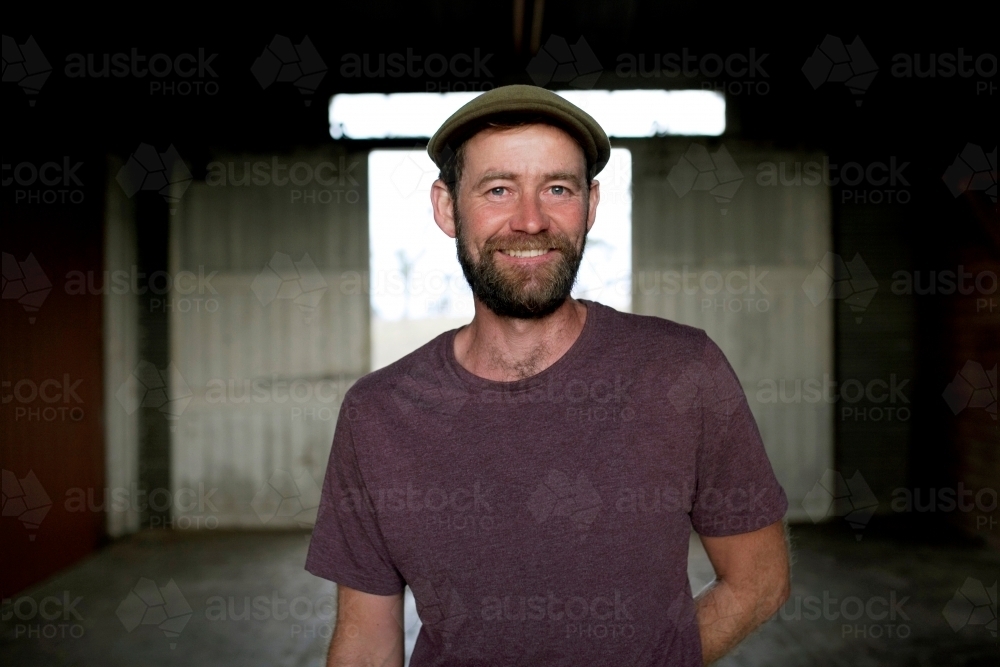 Portrait of a smiling man with background of a dimly lit shed - Australian Stock Image
