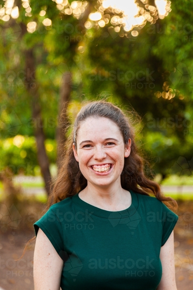 Portrait of a smiling young woman wearing green outside - Australian Stock Image