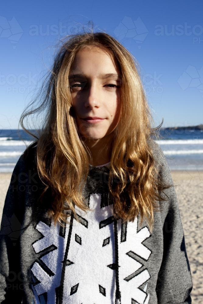 Portrait of a sunlit pre teen girl at the beach in winter - Australian Stock Image