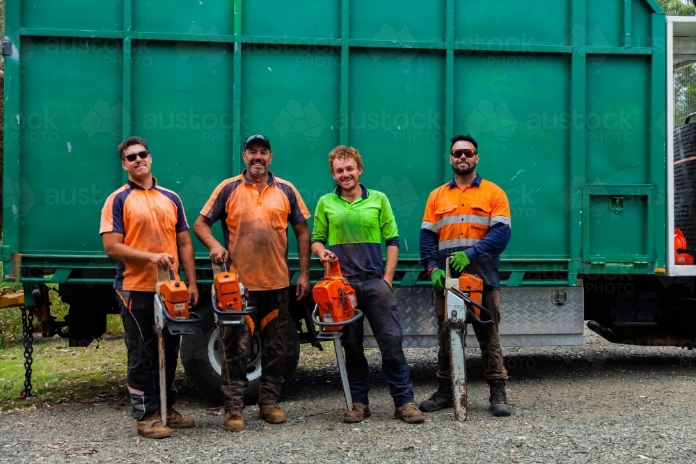 Portrait of a team of men who are tree felling lumberjacks with their chainsaws in front of truck - Australian Stock Image