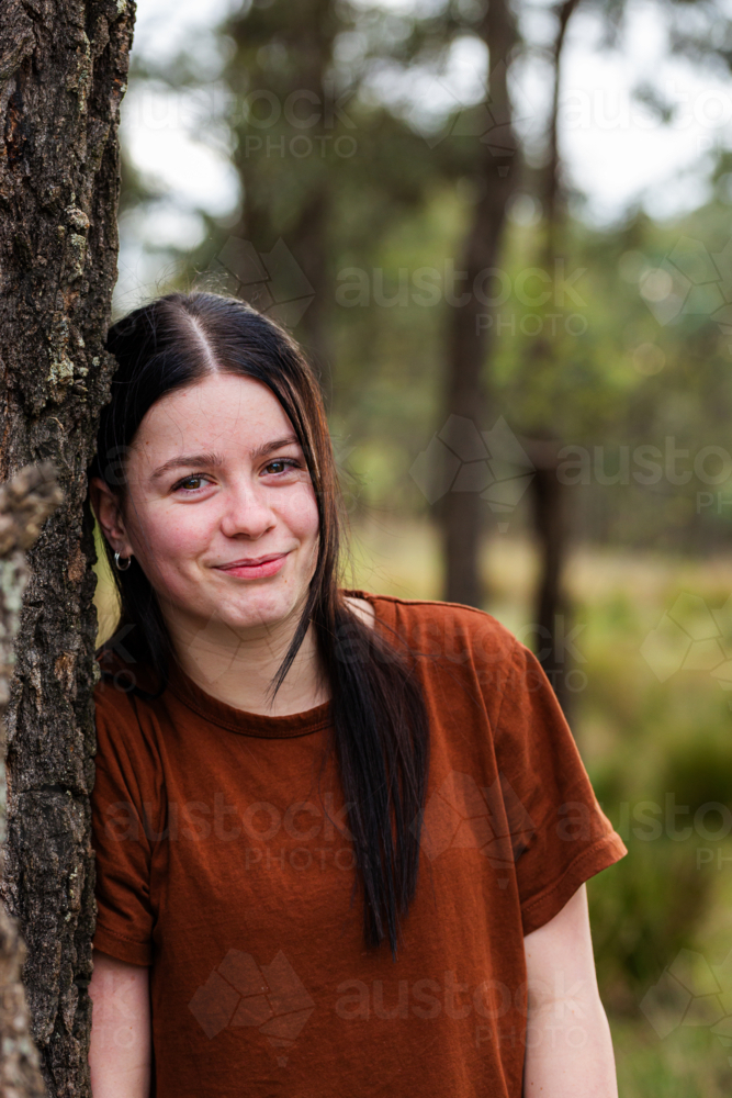 Portrait of a teen girl leaning against the gum tree trunk - Australian Stock Image