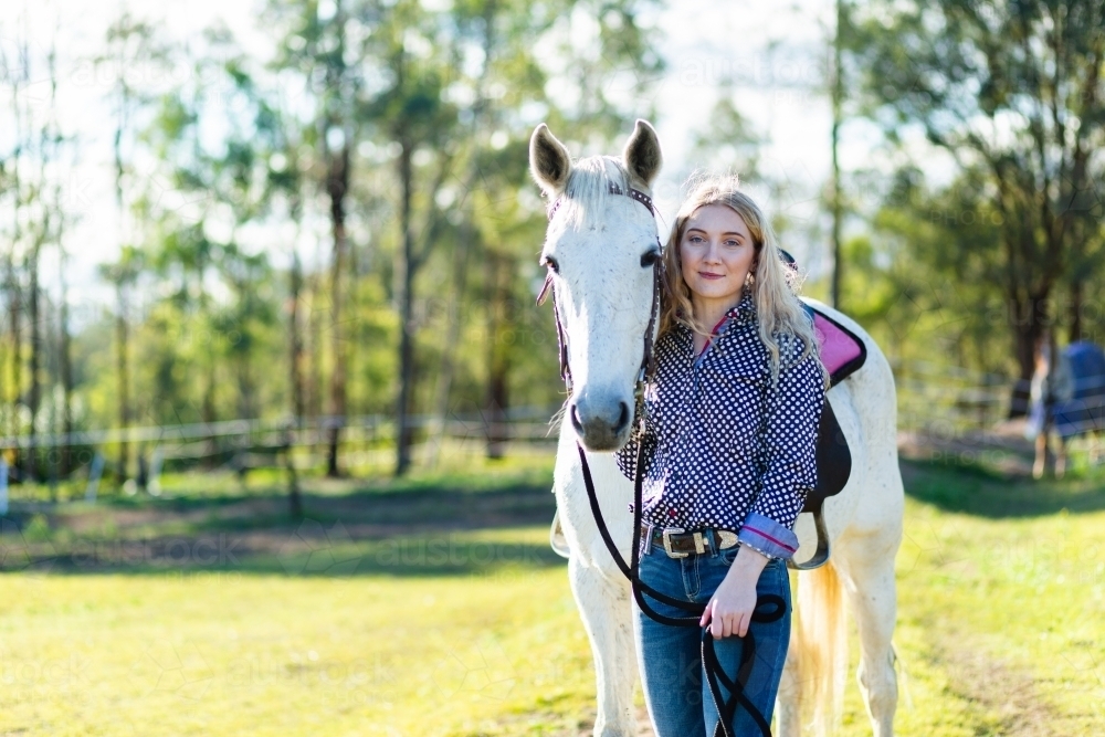 Portrait of a teen horserider in paddock with her horse and copy space - Australian Stock Image