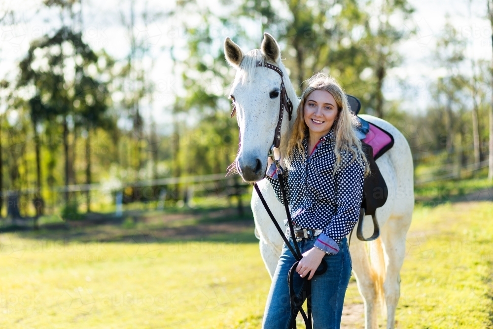 Portrait of a teen horserider in paddock with her horse and copy space - Australian Stock Image