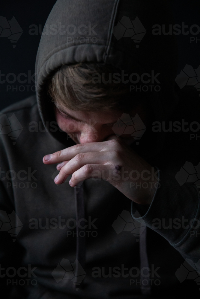 Portrait of a teenage boy laughing and looking down - Australian Stock Image