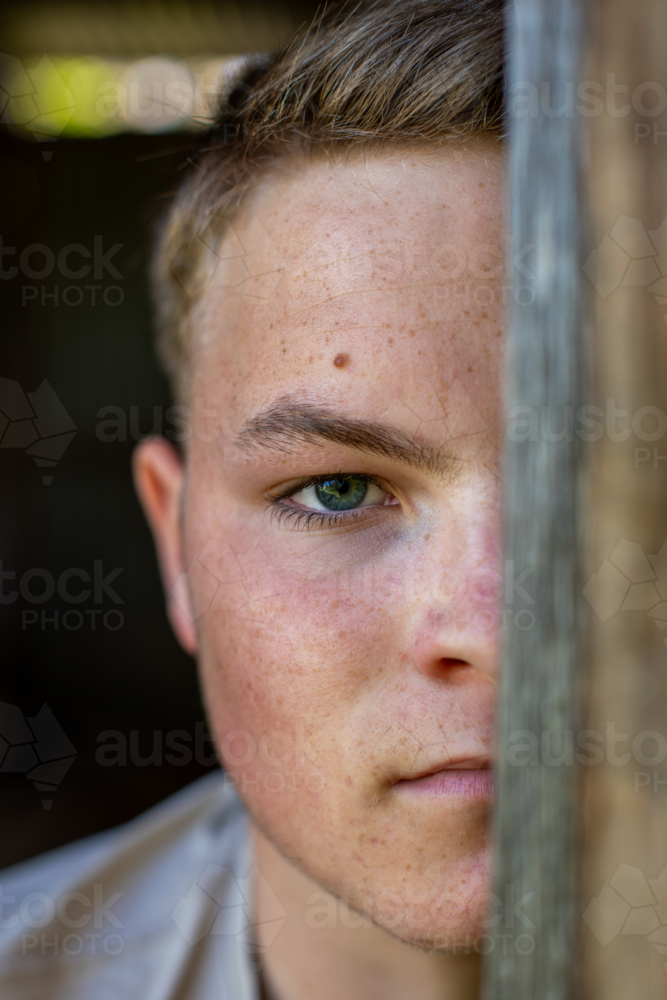 Portrait of a teenage boy looking through a door - Australian Stock Image
