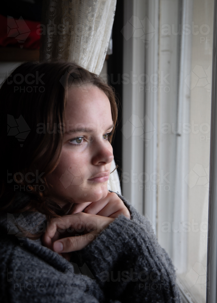 Portrait of a teenage girl looking out a window - Australian Stock Image