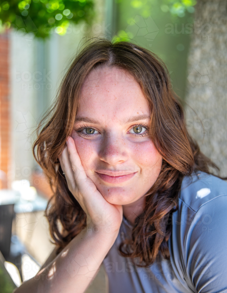 Portrait of a teenage girl under a tree in a grey t-shirt - Australian Stock Image