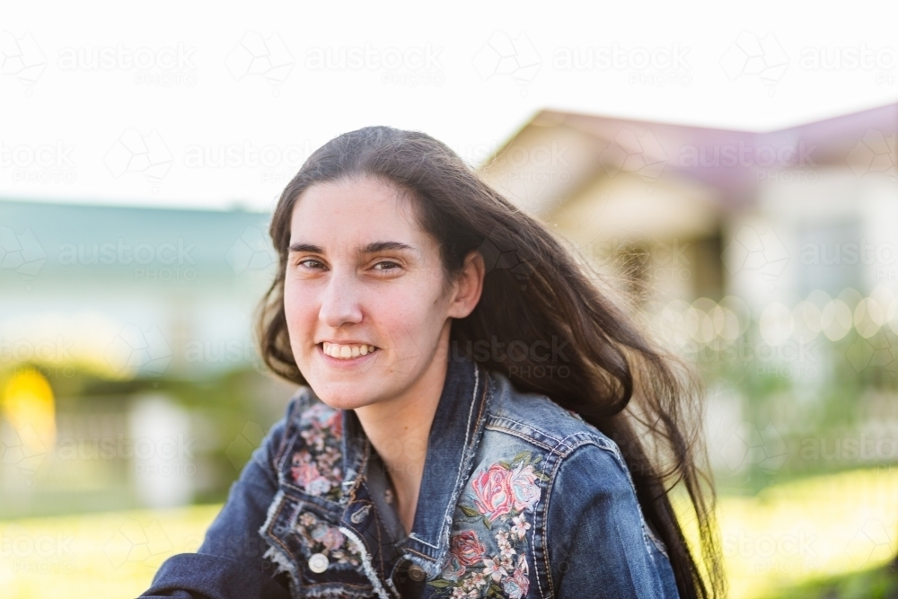 Portrait of a woman in floral jacket outside house - Australian Stock Image