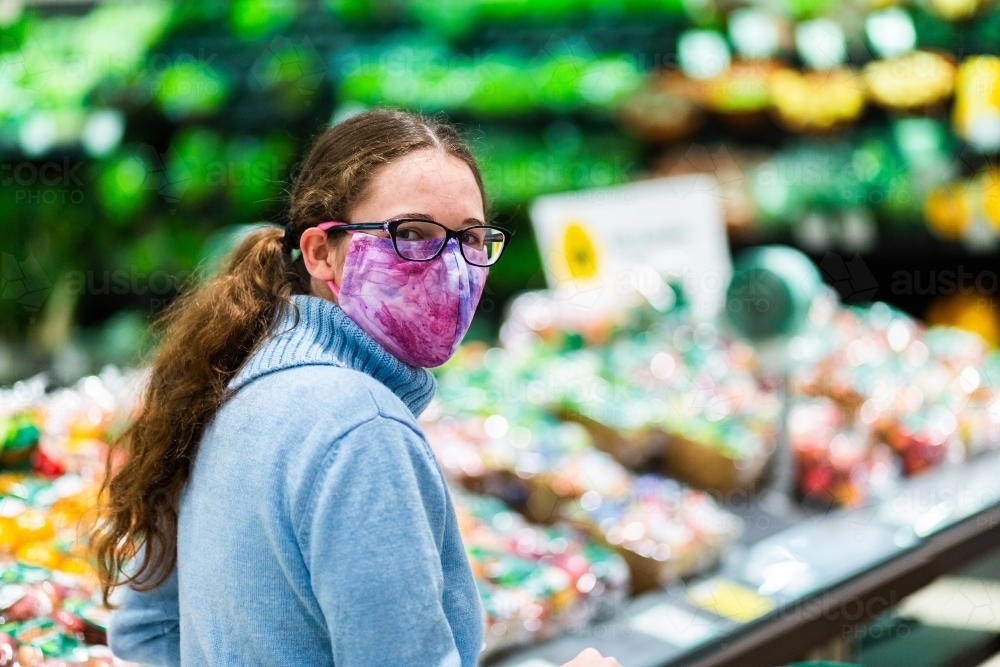 Portrait of a woman in re-usable home made covid-19 face mask doing grocery shopping - Australian Stock Image