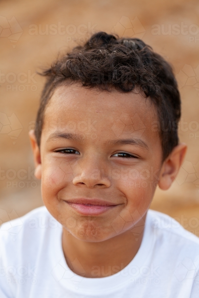 Portrait of a young aboriginal child against brown australian earth - Australian Stock Image