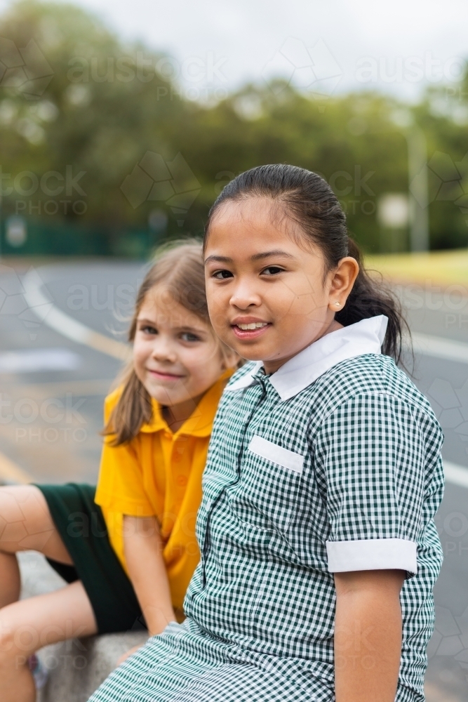 Portrait of a young Australian girl of Filipino ethnicity sitting outside school - Australian Stock Image