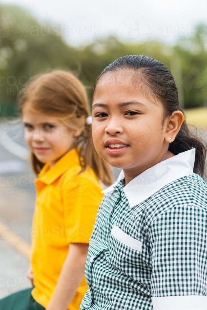 Portrait of a young Australian girl of Filipino ethnicity sitting outside school - Australian Stock Image