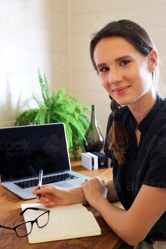Portrait of a young female creative industry worker sitting at her desk - Australian Stock Image