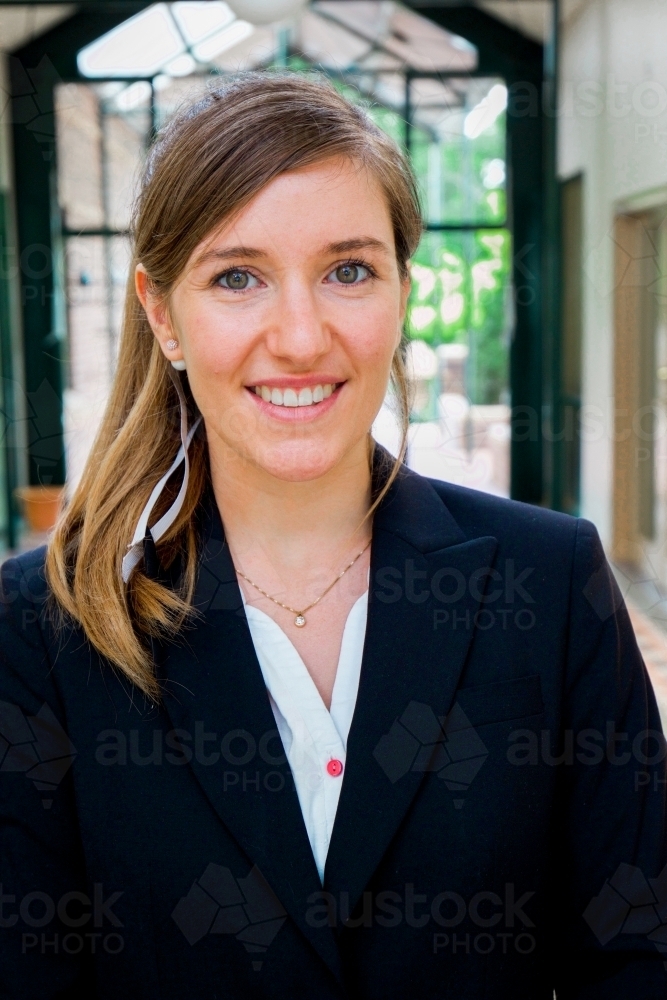 Portrait of a young female office worker standing near the exit of the building - Australian Stock Image