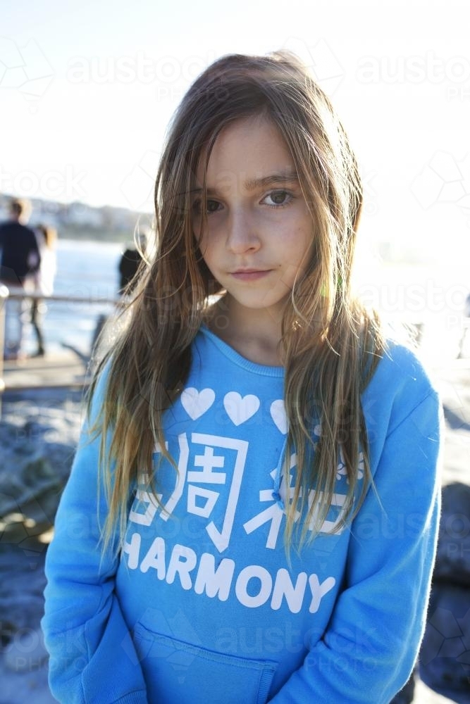 Portrait of a young girl at the beach in winter not smiling - Australian Stock Image