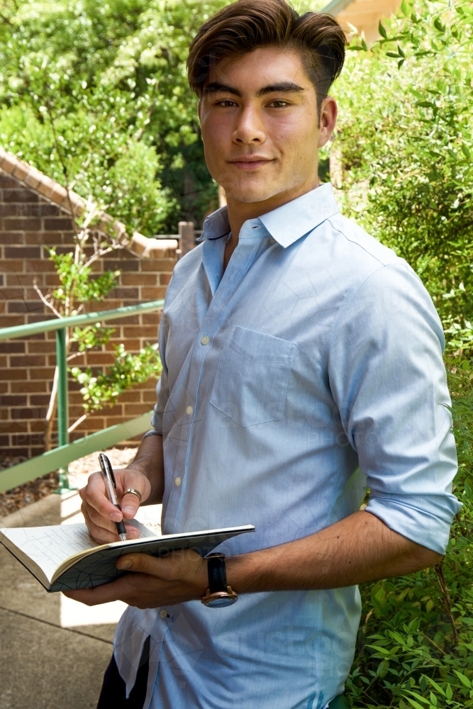 Portrait of a young male outdoors with a notebook - Australian Stock Image