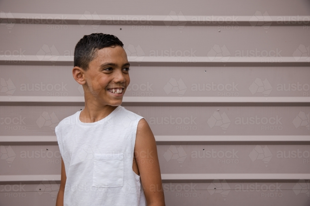Portrait of a young, smiling first nations boy looking away - Australian Stock Image