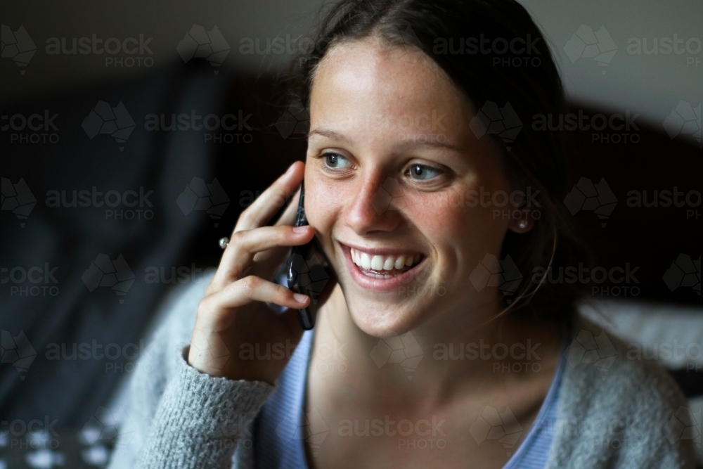 Portrait of a young teenage girl talking on her phone indoors - Australian Stock Image