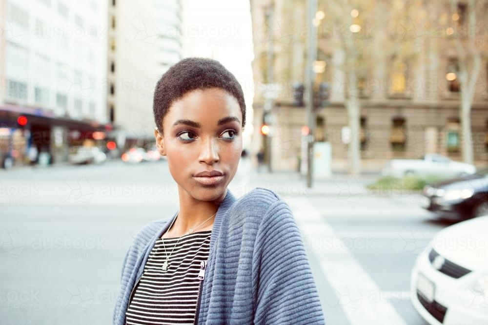 Portrait of a young woman standing in the city looking away - Australian Stock Image