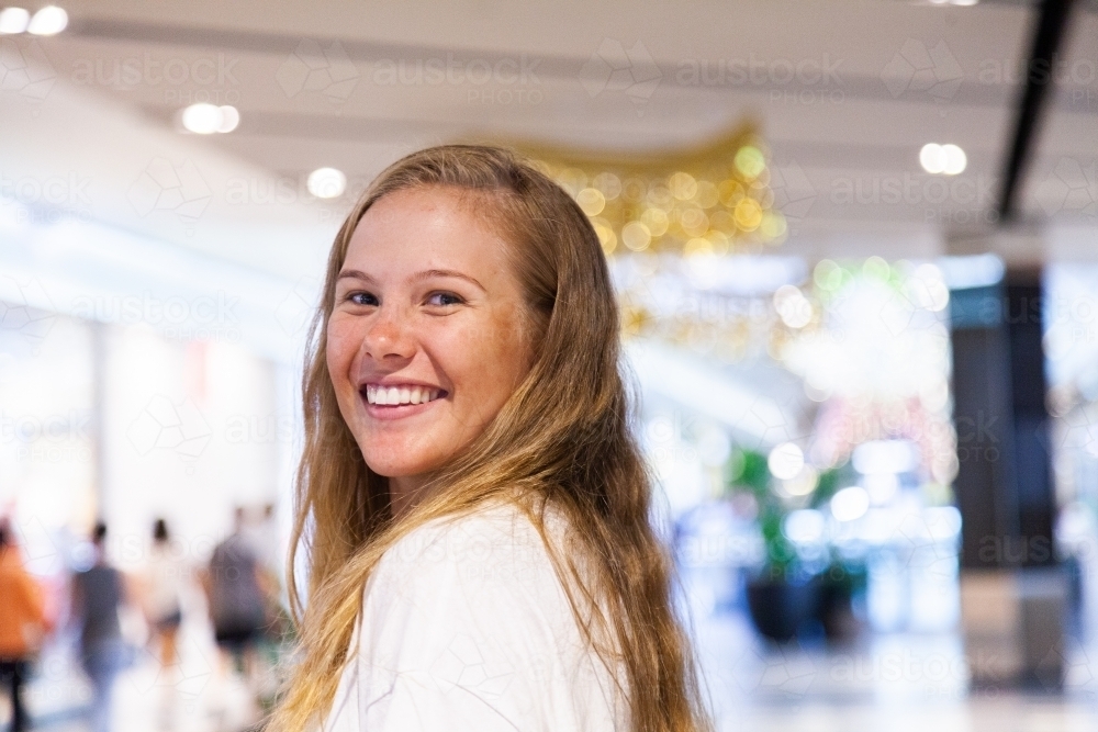 Portrait of a young woman with glowing smile in shopping center - Australian Stock Image