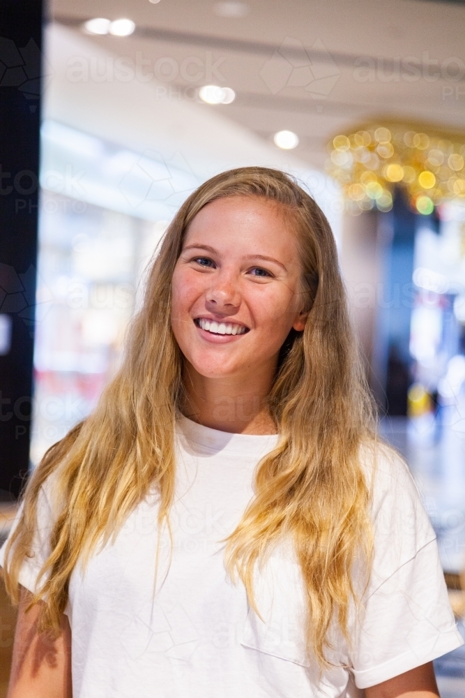 Portrait of a young woman with glowing smile in shopping center - Australian Stock Image