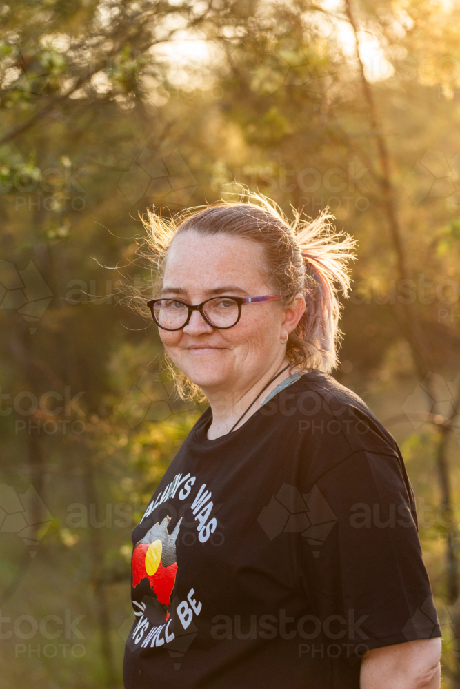 Portrait of Aboriginal Australian woman in golden light in bushland - Australian Stock Image
