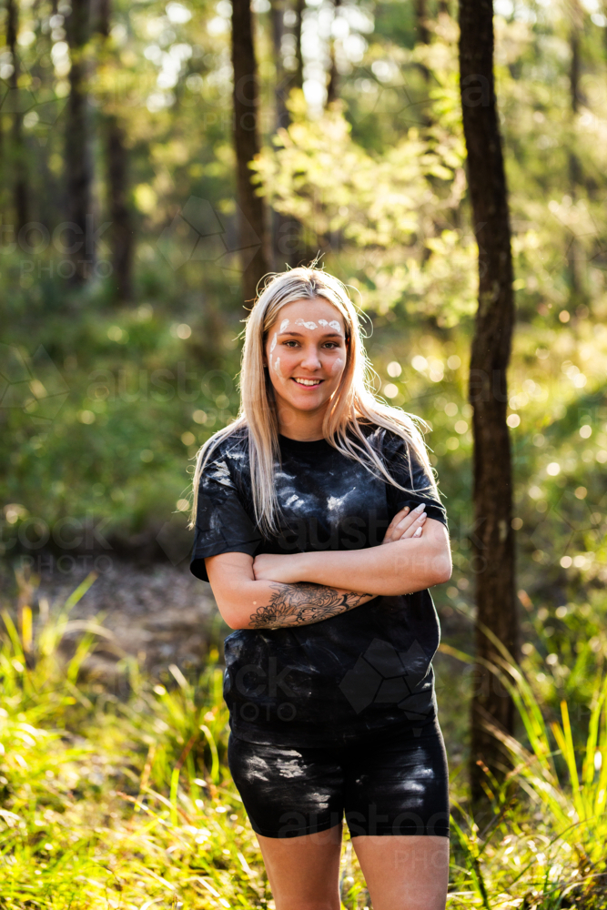 Portrait of Aboriginal Australian woman with arms folded standing in national park bushland - Australian Stock Image
