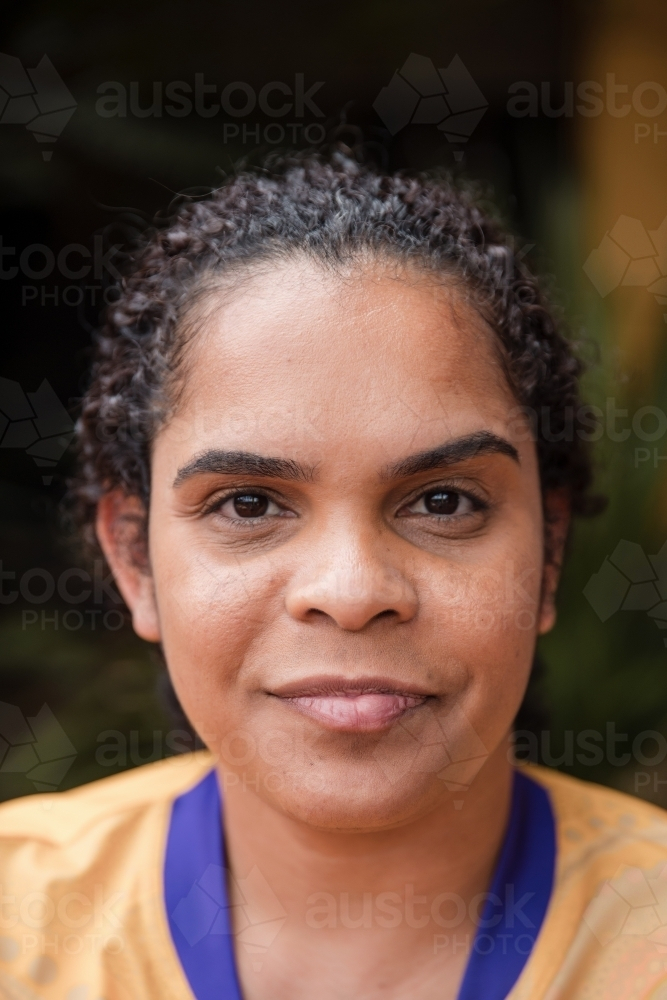 Portrait of Aboriginal woman wearing bright yellow shirt with blue collar - Australian Stock Image