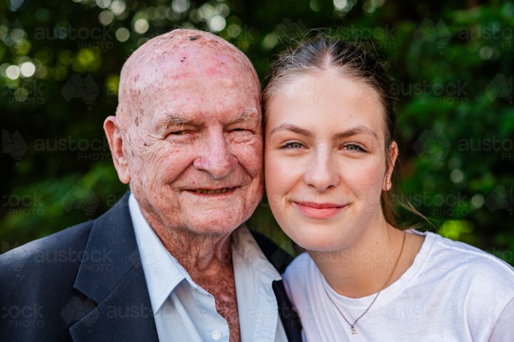 Portrait of an elderly man standing close together with his granddaughter outdoors - Australian Stock Image