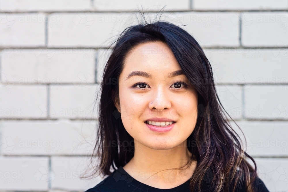 portrait of asian woman against a brick wall - Australian Stock Image