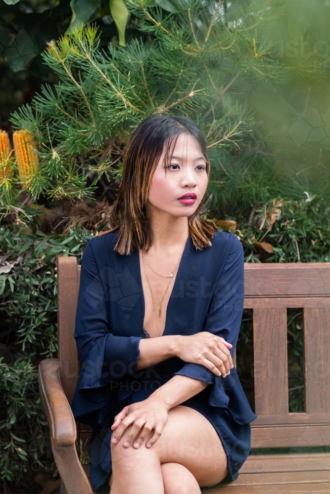 portrait of beautiful asian woman sitting on park bench - Australian Stock Image