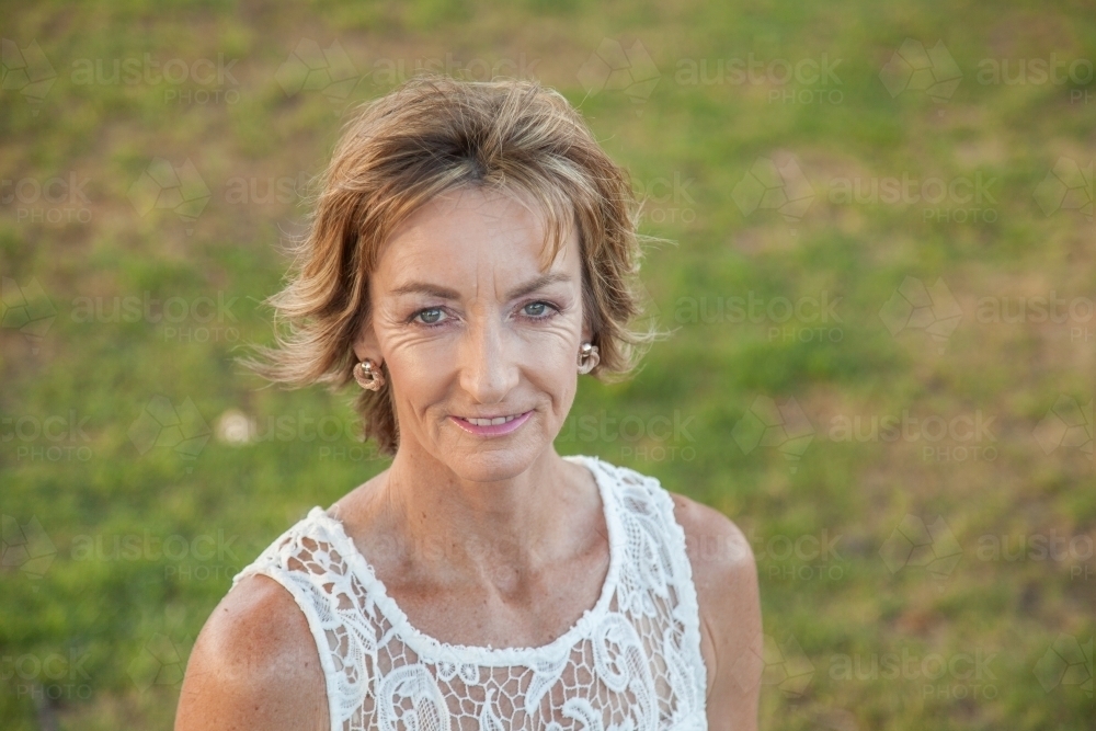 Portrait of beautiful middle aged lady with green grassy backdrop outdoors - Australian Stock Image