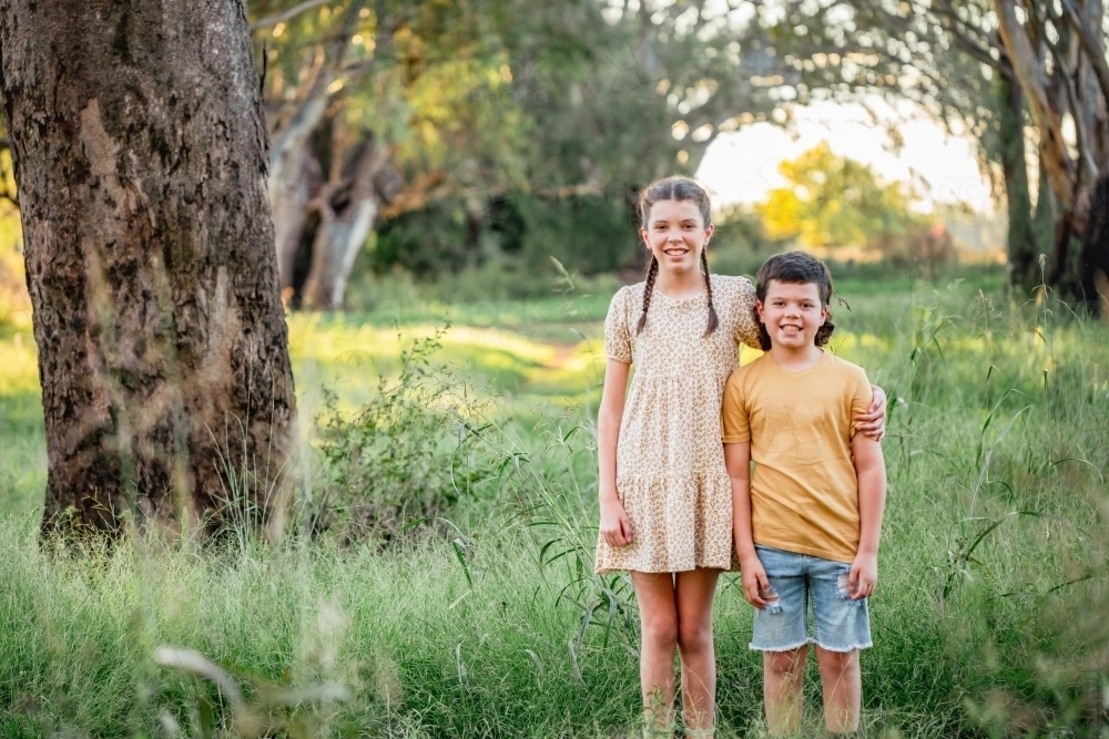 Portrait of bother and sister standing together in Australian country bush setting - Australian Stock Image