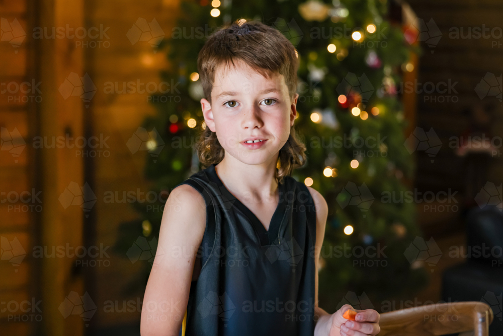Portrait of boy in front of Christmas tree - Australian Stock Image