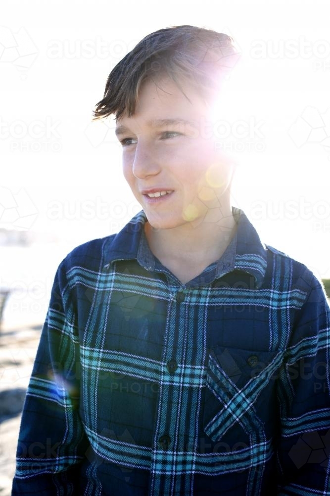 Portrait of boy looking to the side with afternoon glare - Australian Stock Image