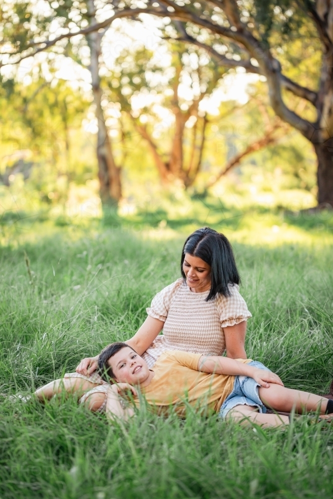 Portrait of boy lying on mothers lap in rural country bush setting - Australian Stock Image