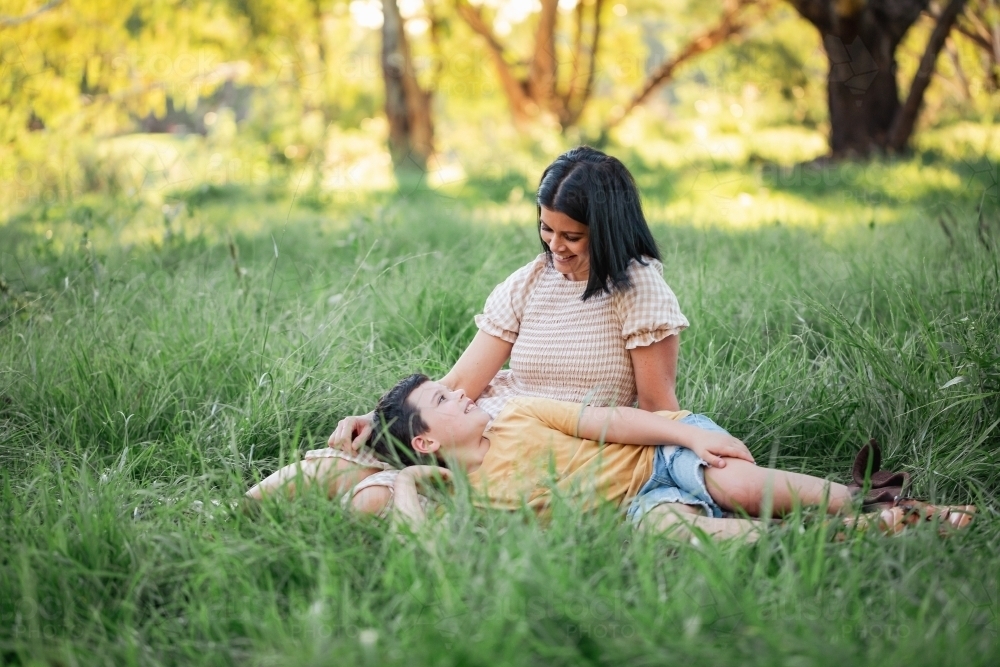 Portrait of boy lying on mothers lap in rural country bush setting - Australian Stock Image