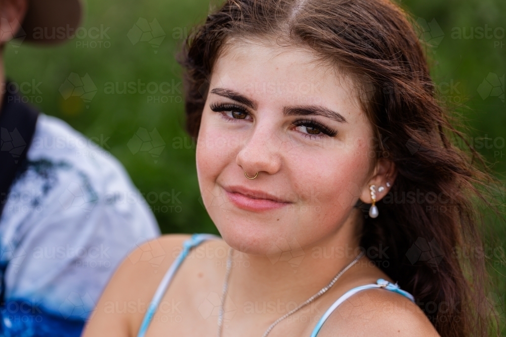 Portrait of brunette young lady relaxing outside by a lake with friends - Australian Stock Image