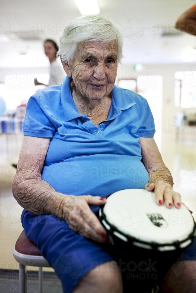 Portrait of elderly lady during bongo drumming session at retirement village - Australian Stock Image