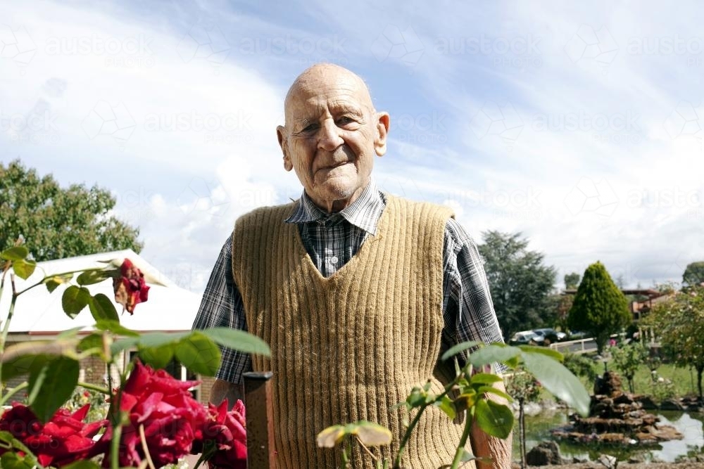 Portrait of elderly man standing in a rose garden at an aged care facility - Australian Stock Image