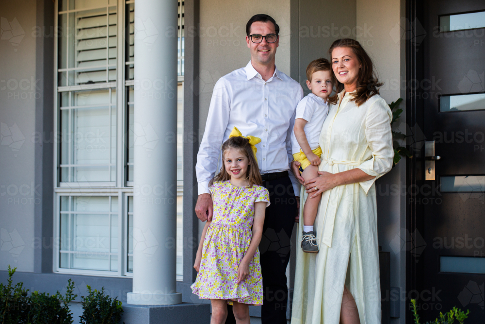 Portrait of family of four standing together outside home dad mum and two children - Australian Stock Image