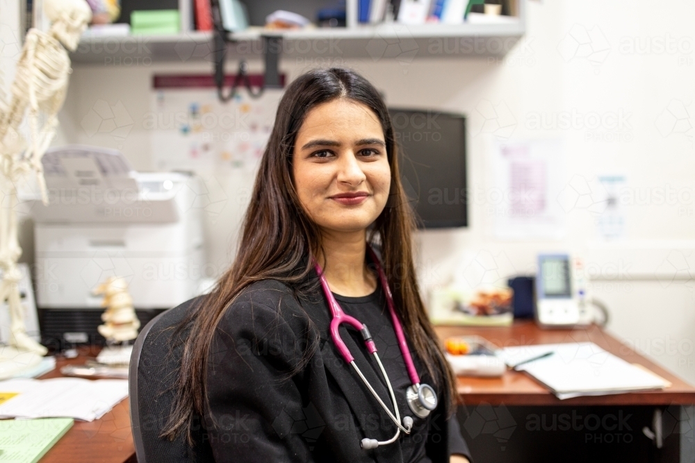 portrait of female doctor in her medical office looking at camera smiling - Australian Stock Image